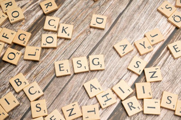 Rozsypane klocki z gry Scrabble. Trzy z nich układają się w słowo ESG.
