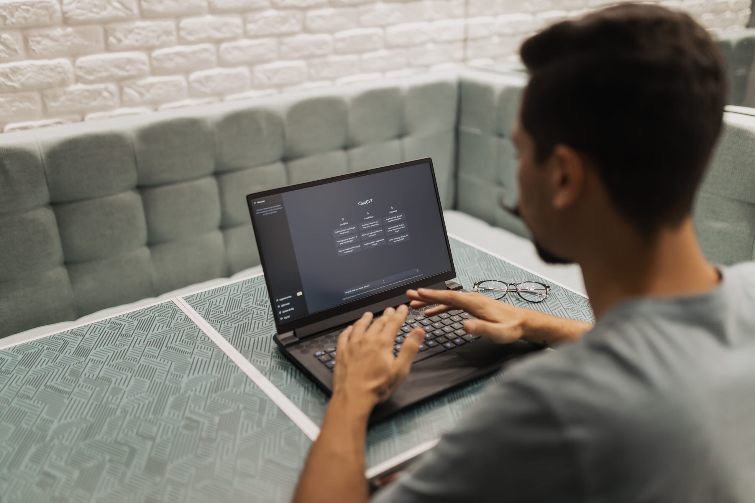 Mężczyzna siedzi przy laptopie, korzysta z Chata GPT.